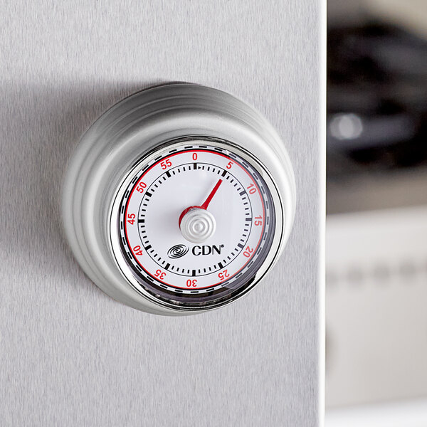 A close up of a CDN silver mechanical kitchen timer.