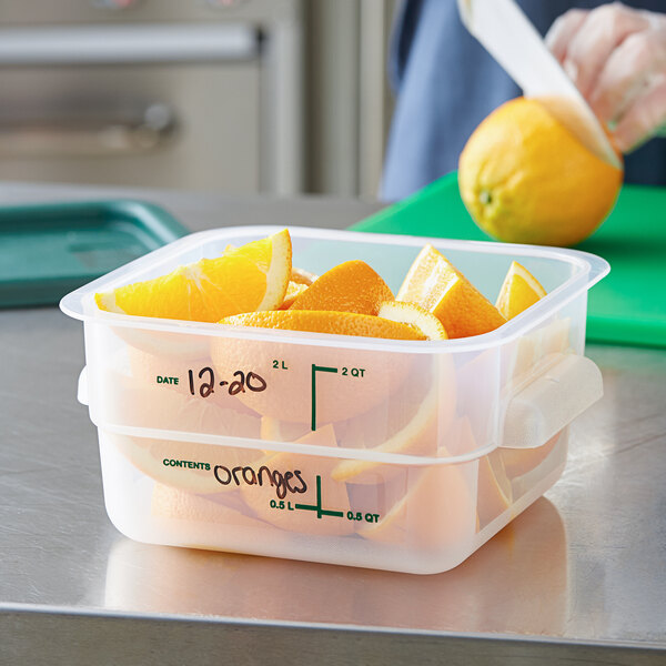 A woman cutting oranges into a Vigor translucent square food storage container.