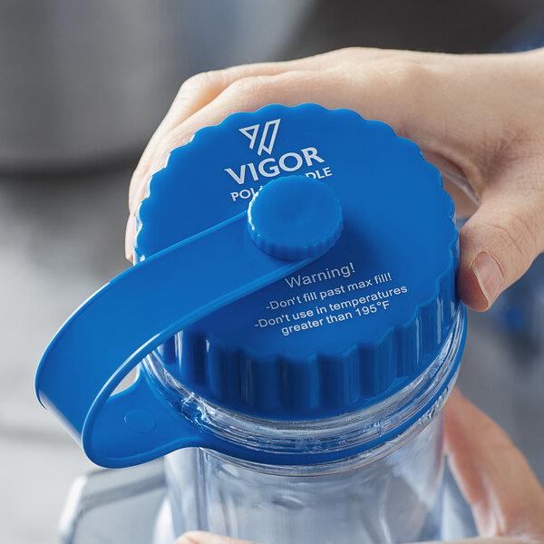 A hand holding a blue plastic circular cap.