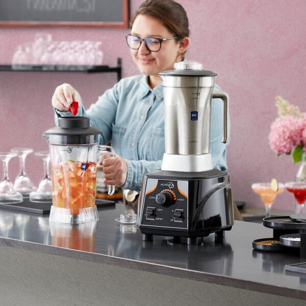 A woman making a drink in an AvaMix commercial blender.