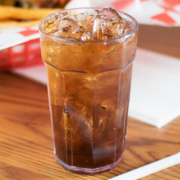 A Cambro Laguna plastic tumbler filled with brown liquid and ice on a table.