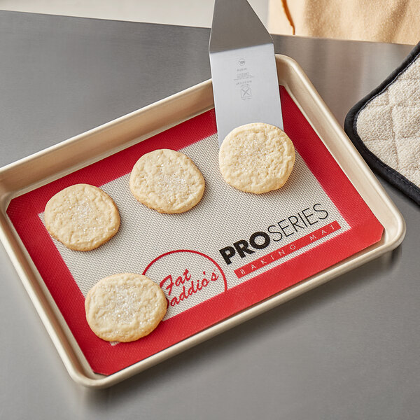 A Fat Daddio's quarter size silicone baking mat on a tray with cookies.