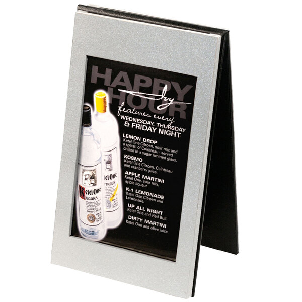 A Menu Solutions aluminum menu tent with a brushed silver finish holding a menu with a picture of bottles on a table.