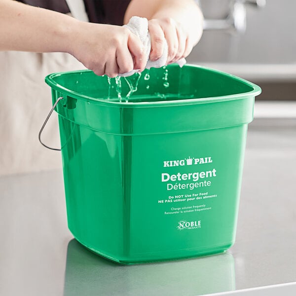 A person washing a green Noble Products King-Pail with detergent.
