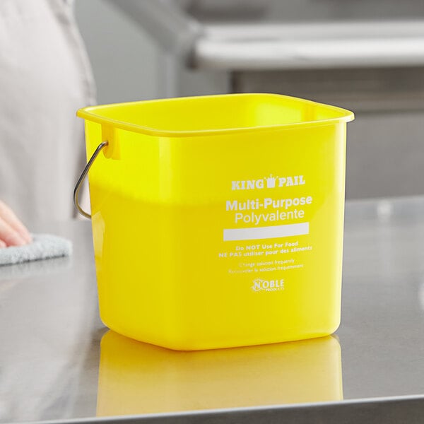 A close-up of a yellow Noble Products King-Pail on a counter.
