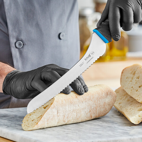 A person using a Schraf serrated bread knife to cut a loaf of bread.