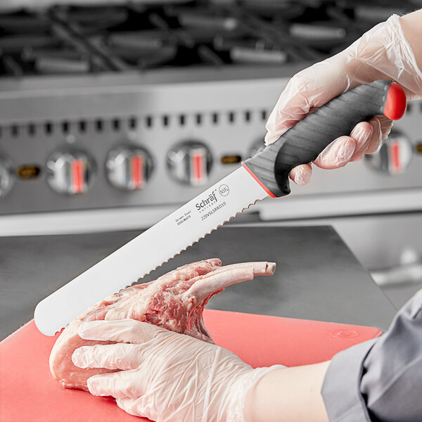 A person in gloves using a Schraf serrated slicing knife to cut meat.