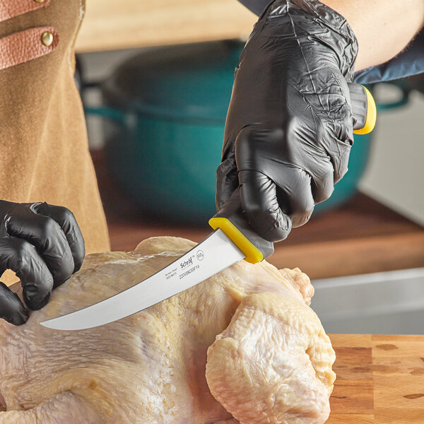 A person in black gloves using a Schraf yellow curved boning knife to cut chicken.