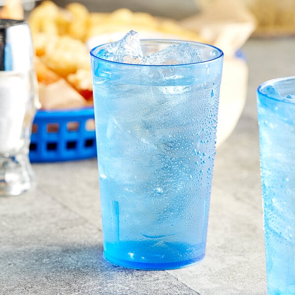 Two blue Choice plastic tumblers filled with ice water on a table.
