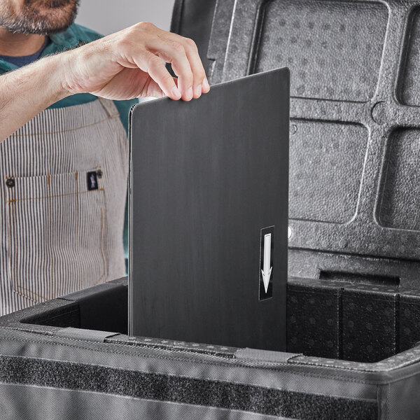 A man opening a black box to take out a black rectangular divider with a white arrow.