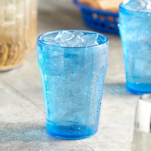 A close up of a Choice blue plastic tumbler with ice and a straw.