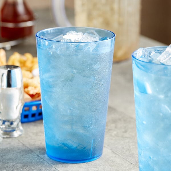 Two blue Choice plastic tumblers with ice on a table.