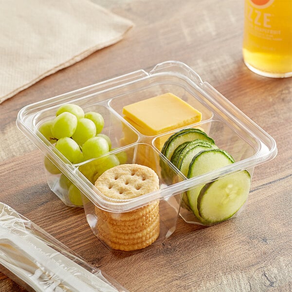 A Dart plastic container with crackers, grapes, and cheese.