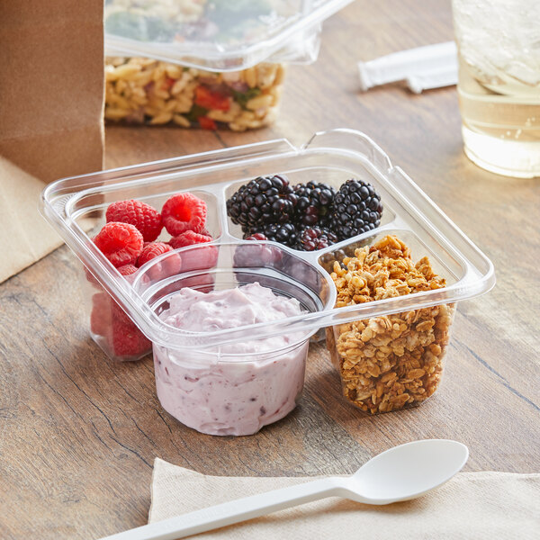 A Dart TamperGuard plastic container with granola, berries, and yogurt on a table.