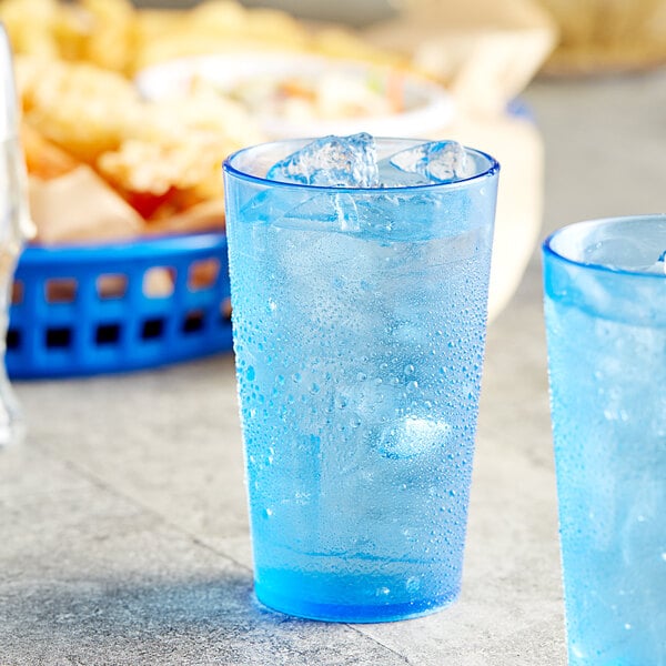 Two Choice blue plastic tumblers filled with ice on a table with food.