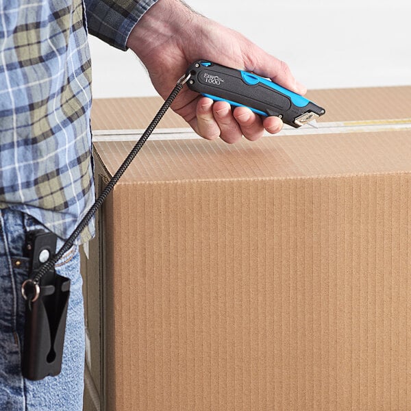 A person holding a Garvey blue and black box cutter with a lanyard and holster.
