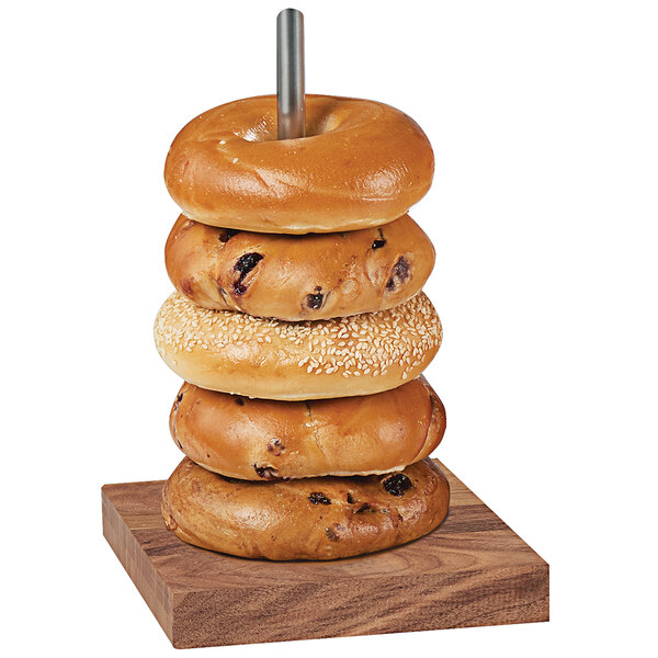 A stack of bagels on a wooden and chrome display pole.