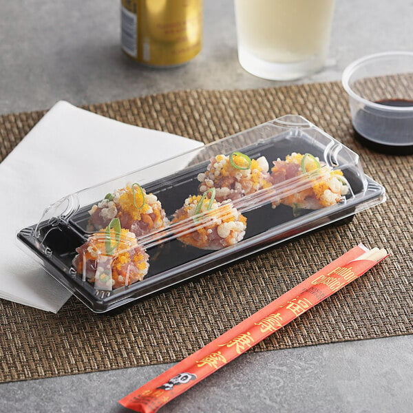A plastic container with sushi in it on a place mat.