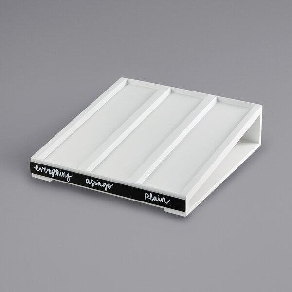 A white rectangular Cal-Mil bagel holder base with black writing on it.
