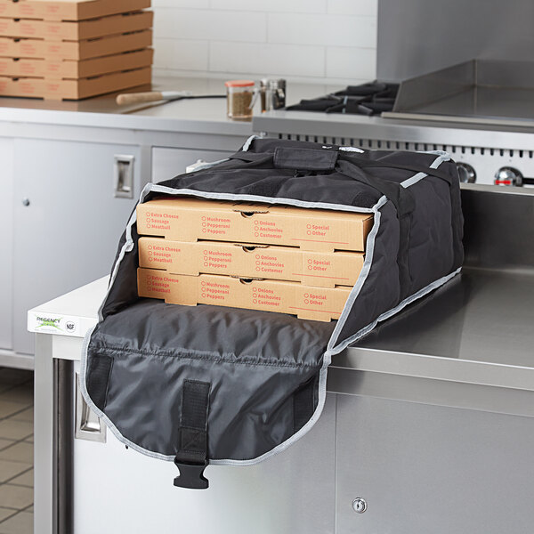 A black Vollrath insulated pizza delivery bag holding three pizza boxes.