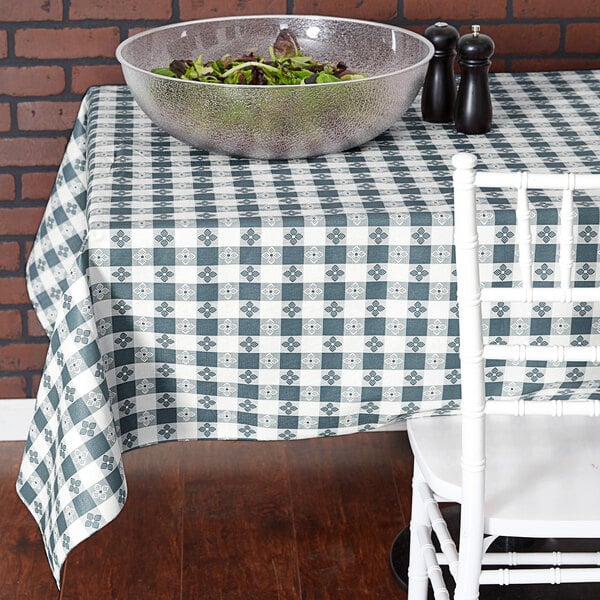 A table with a bowl of salad on it covered with a blue and white checkered Intedge vinyl table cover.