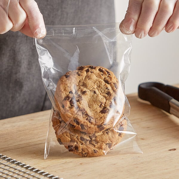 A hand holding a Choice resealable plastic bag of chocolate chip cookies.