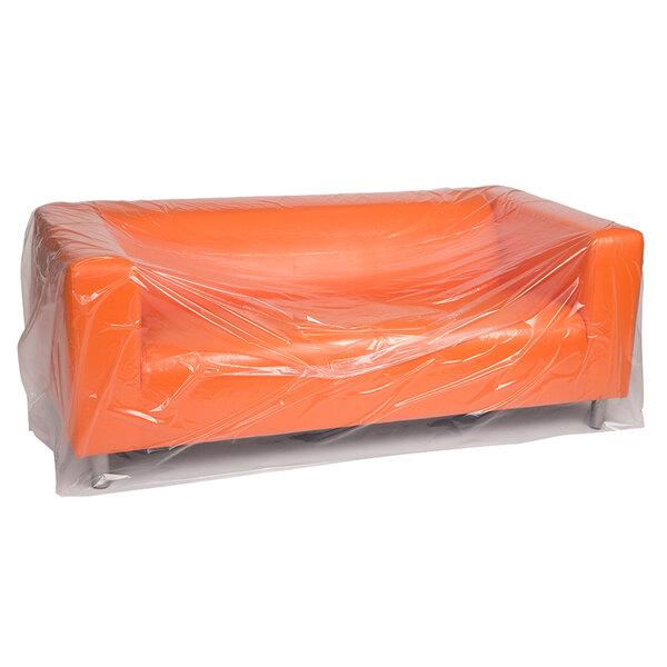 A clear plastic Lavex furniture bag covering an orange couch.