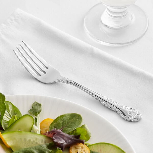 An Acopa Capulet stainless steel salad fork on a plate of salad.