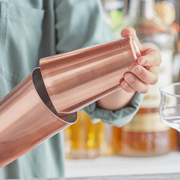A person holding an Acopa copper cocktail shaker.