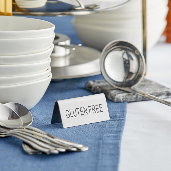 A table with a stainless steel "Gluten Free" table tent sign.