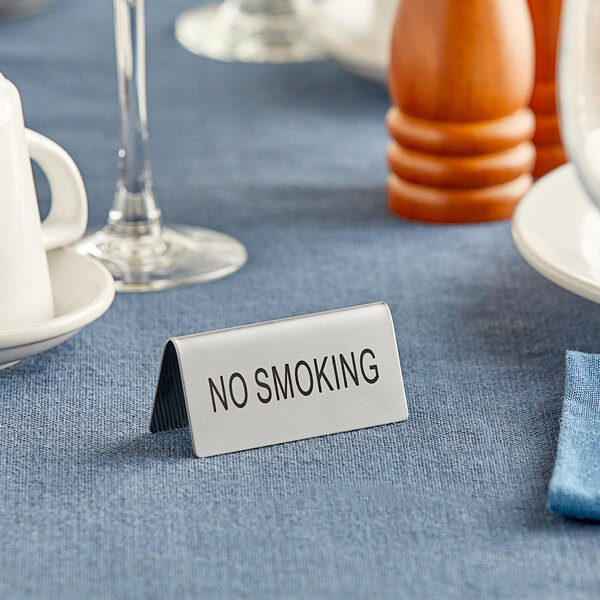 A stainless steel "No Smoking" table tent sign on a table.