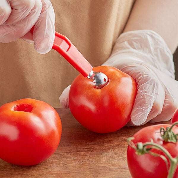 A person using a Choice Tomato Corer to core a tomato.