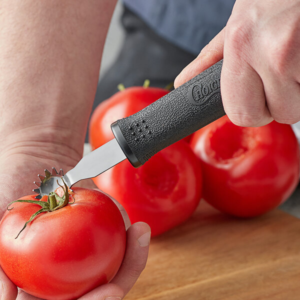 A person using a Choice Tomato Corer to cut a tomato.