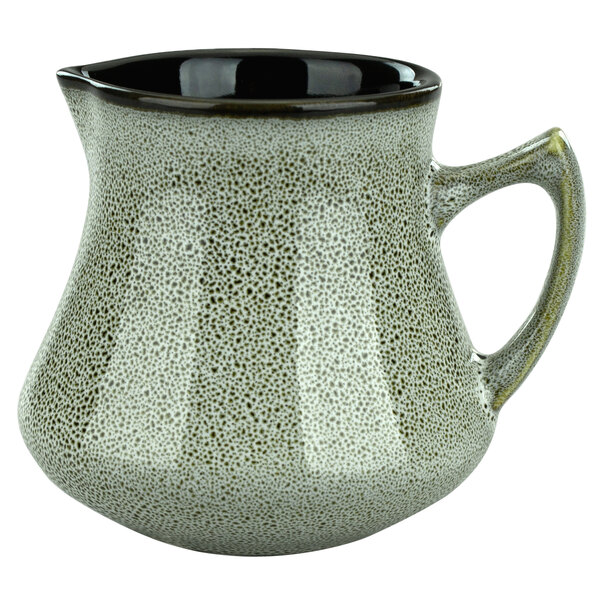 A white porcelain creamer with a black rim and gray speckles and a handle.