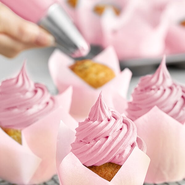 A close-up of a cupcake with pink frosting made with Chefmaster Bakers Rose food coloring.