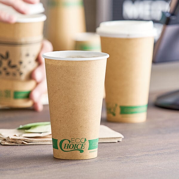 A person's hand holding a brown EcoChoice paper hot cup with a green lid.