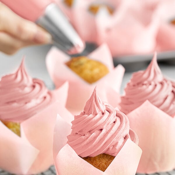 A close-up of a cupcake with pink frosting made using Chefmaster Deep Pink food coloring.