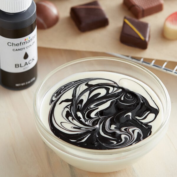 A bowl of white liquid with black swirls from Chefmaster Black Oil-Based Candy Color.