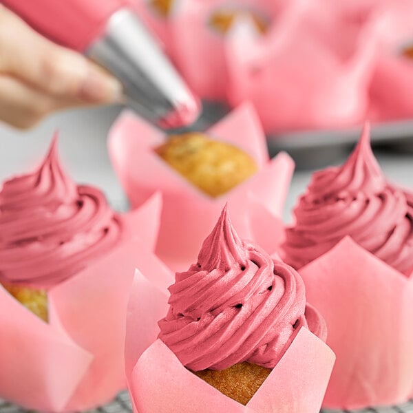 A close up of a cupcake with pink frosting.