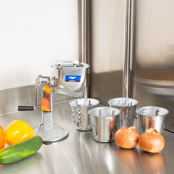 A Vollrath King Kutter food processor on a stainless steel counter with vegetables and metal containers.