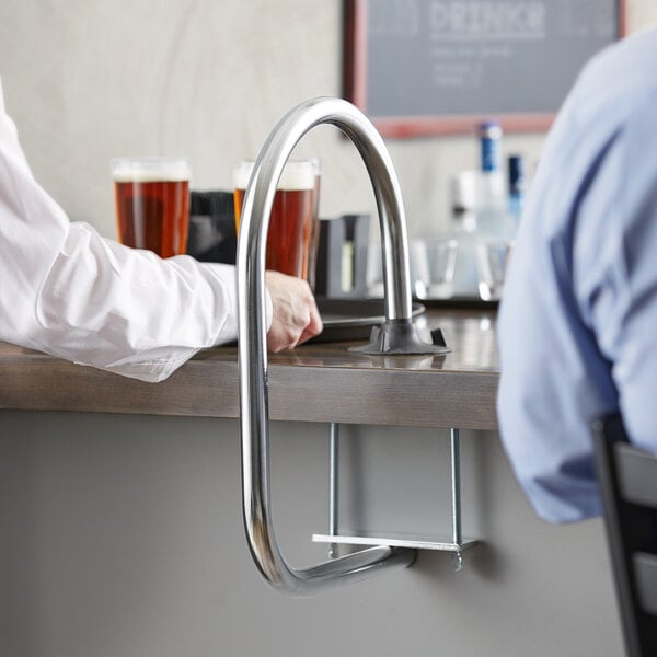 A person using a Lancaster Table & Seating waitress stall to hold a beer glass.