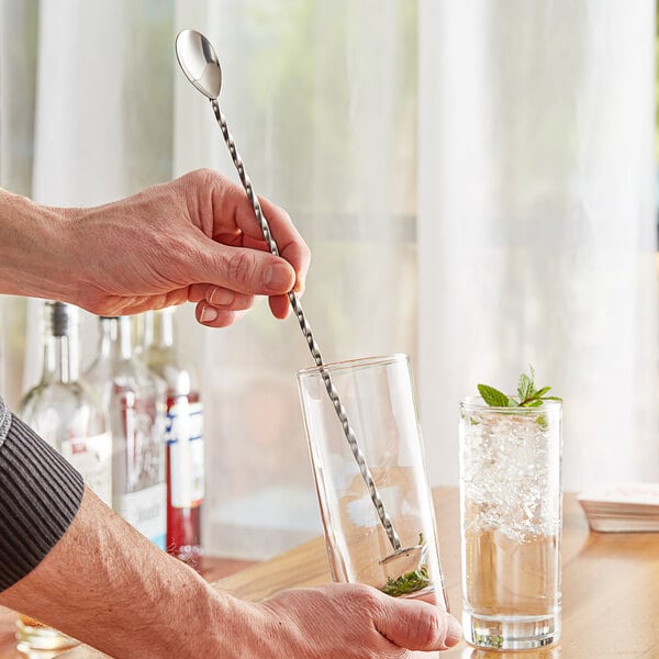 A man using an Acopa silver bar spoon in a glass.