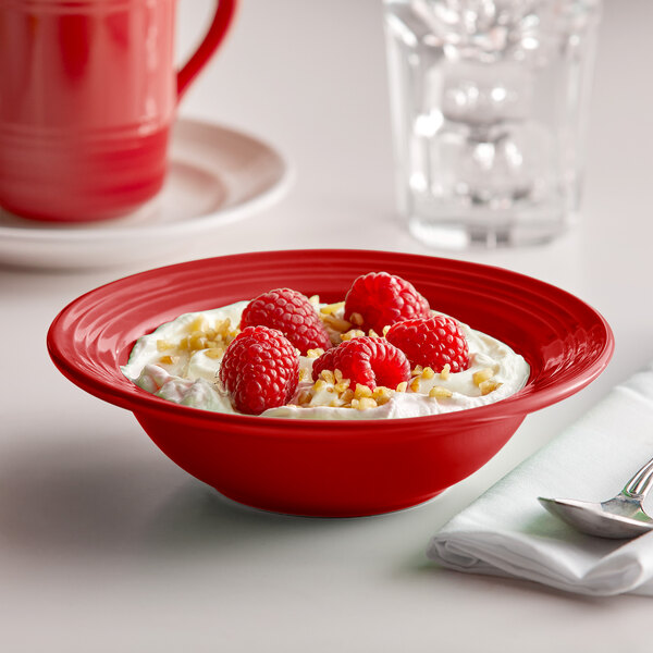 A Tuxton Concentrix cayenne grapefruit bowl filled with food with raspberries and nuts.