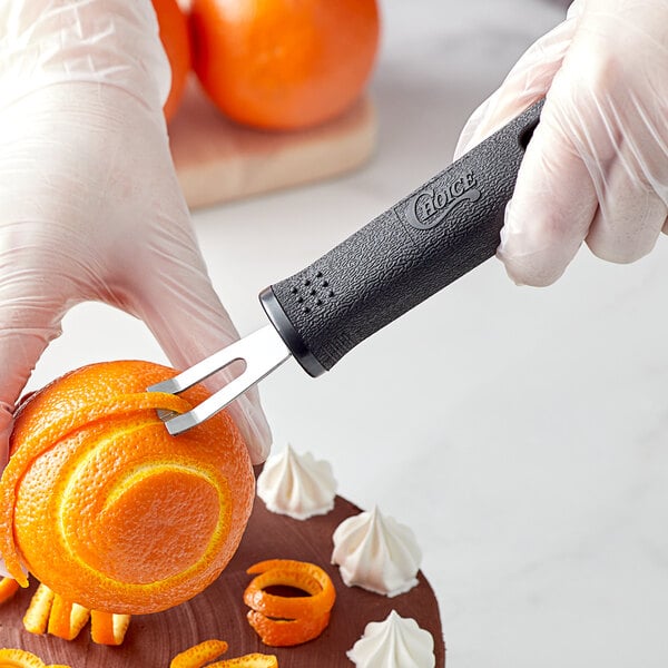 A hand in a glove using a Choice channel knife to carve an orange.