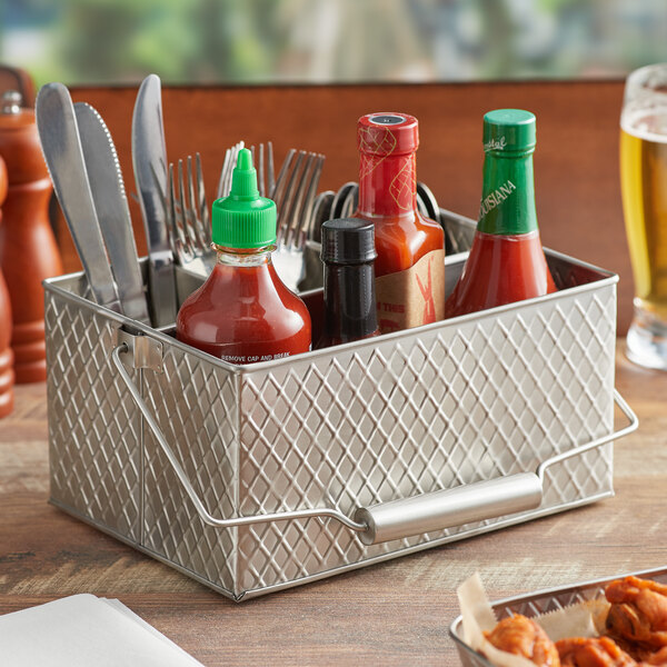 A Tablecraft lattice stainless steel flatware and condiment caddy on a table with utensils and condiments.