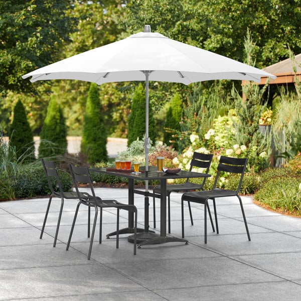 A white Lancaster Table & Seating umbrella over a patio table with chairs.
