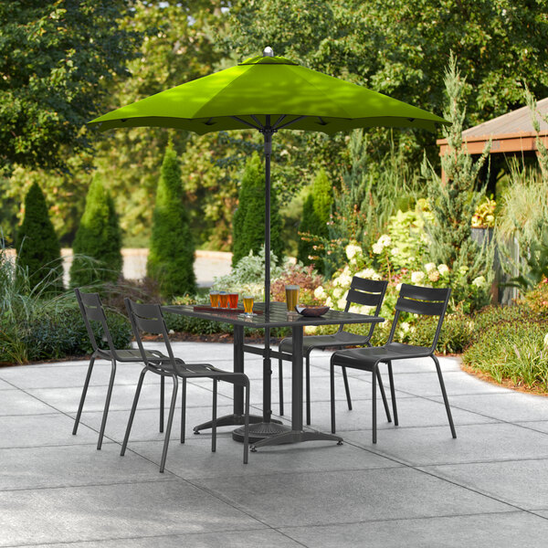 A Lancaster Table & Seating moss green umbrella over a table with chairs on an outdoor patio.
