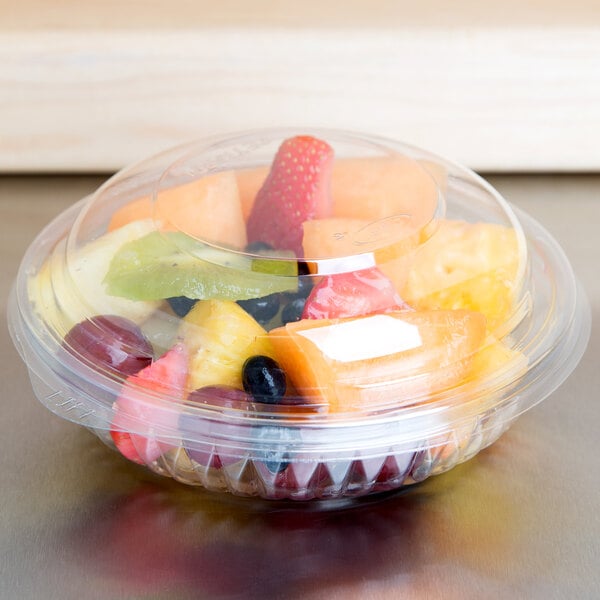 A Dart clear plastic bowl filled with fruit.