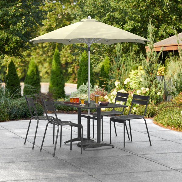 A Lancaster Table & Seating umbrella over a table and chairs on a patio.
