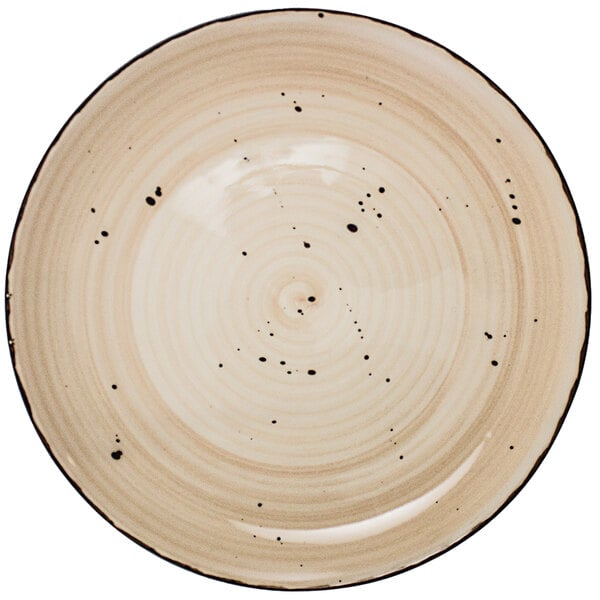 A close-up of an International Tableware Rotana wheat coupe porcelain plate with black dots.